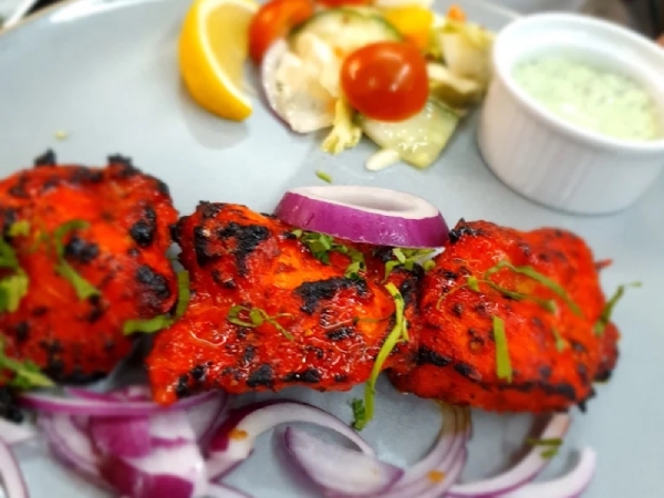 Mallroad House's sizzling plate of red-marinated Chicken Tikka and onions garnished with cilantro. 